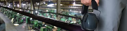Man's hand holding hearing protection in a plant