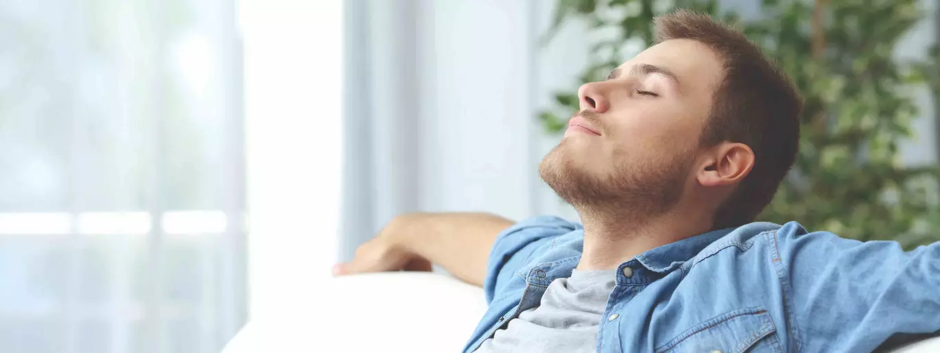 Man breathing on his sofa, eyes closed